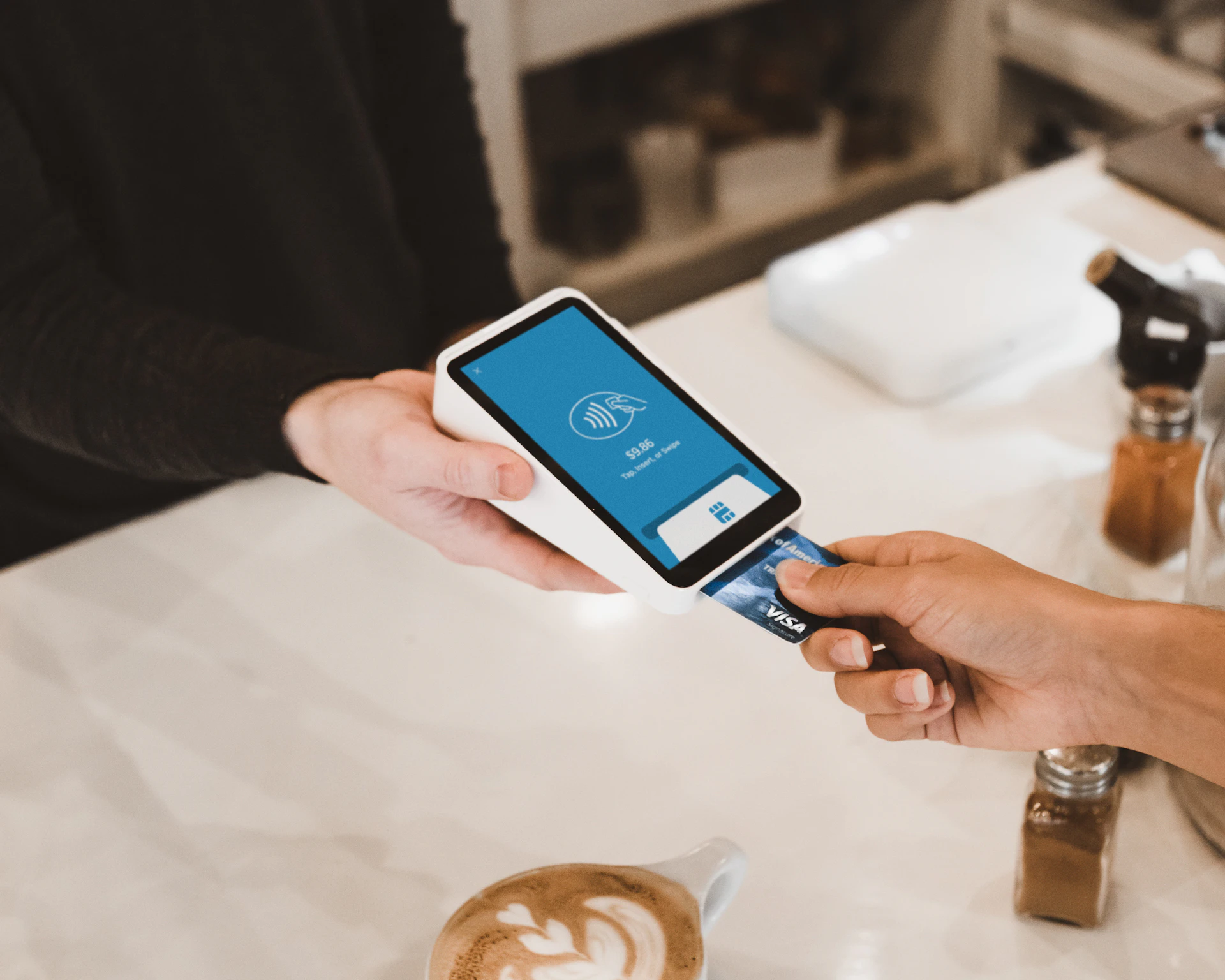 A customer paying contactless with a phone at a café counter