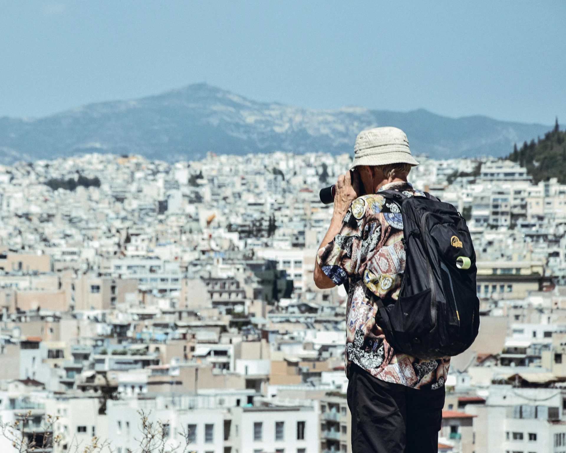 A traveller with a backpack looking out over a city of white buildings