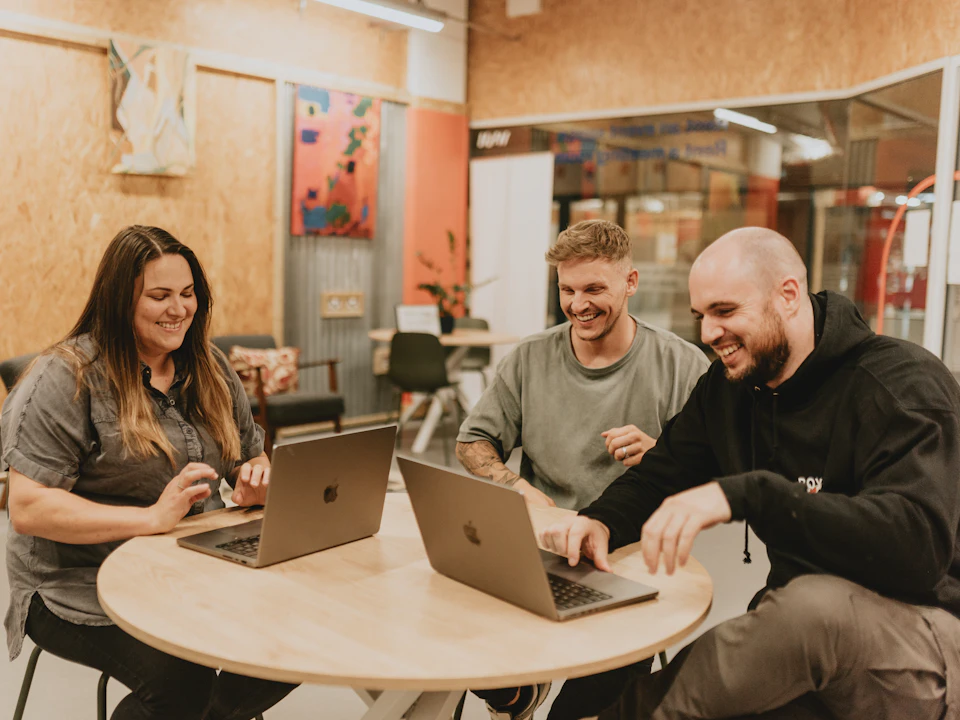 Three colleagues laughing as they work at a table