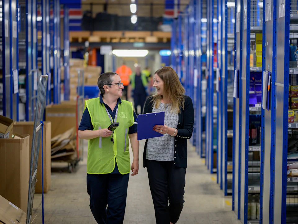 Two women walking through a warehouse aisle