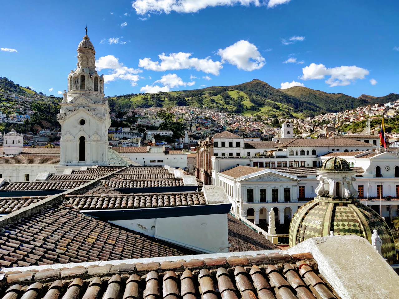 Weiße Kirchtürme in der Altstadt von Quito unter grünen Bergen
