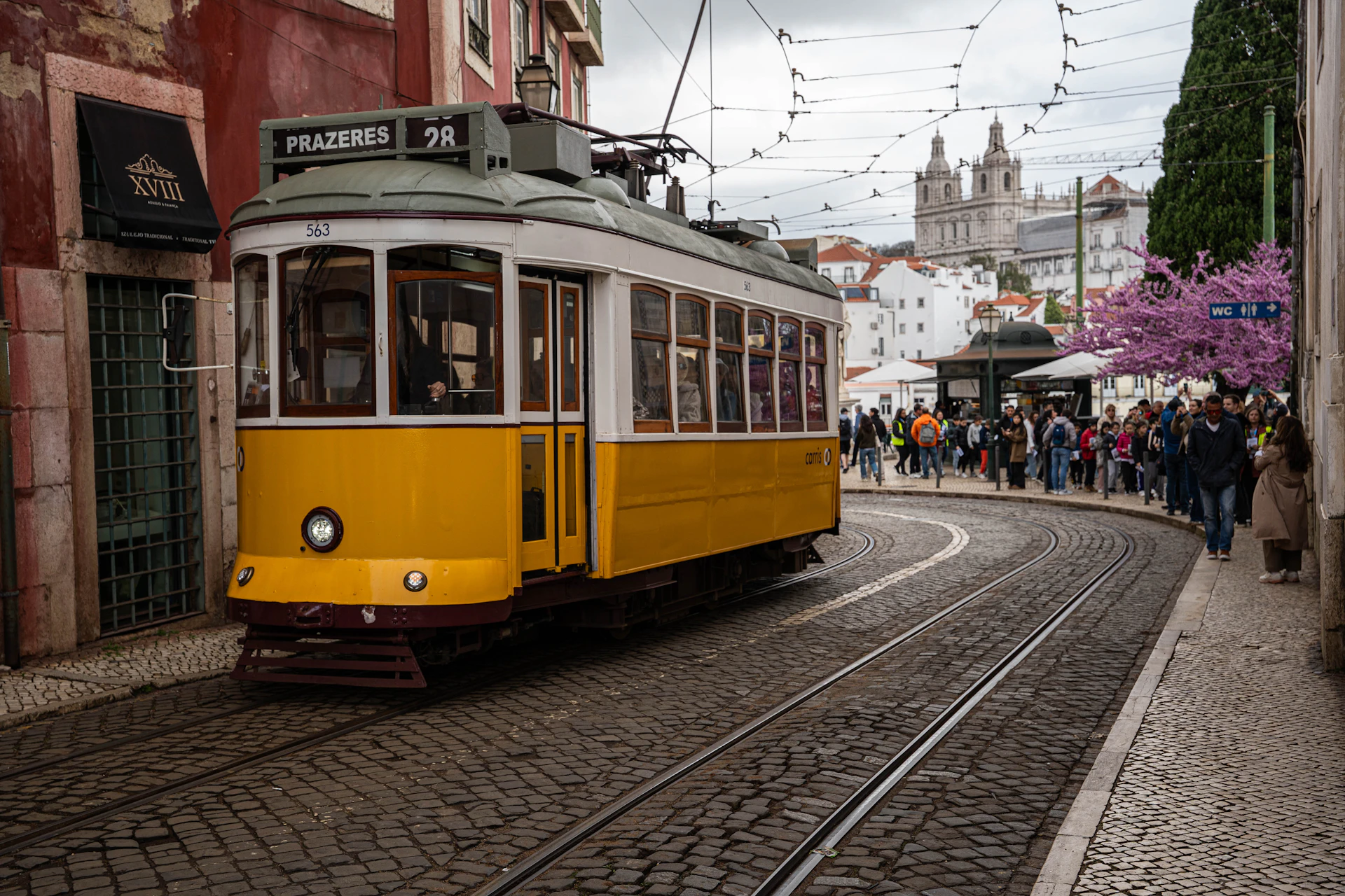 Eine gelbe Straßenbahn fährt eine Straße in Lissabon hinauf