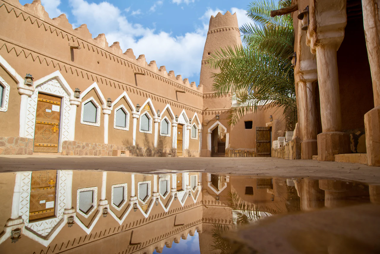 بيوت من الطين تنعكس على الماء في قرية أشيقر التراثية