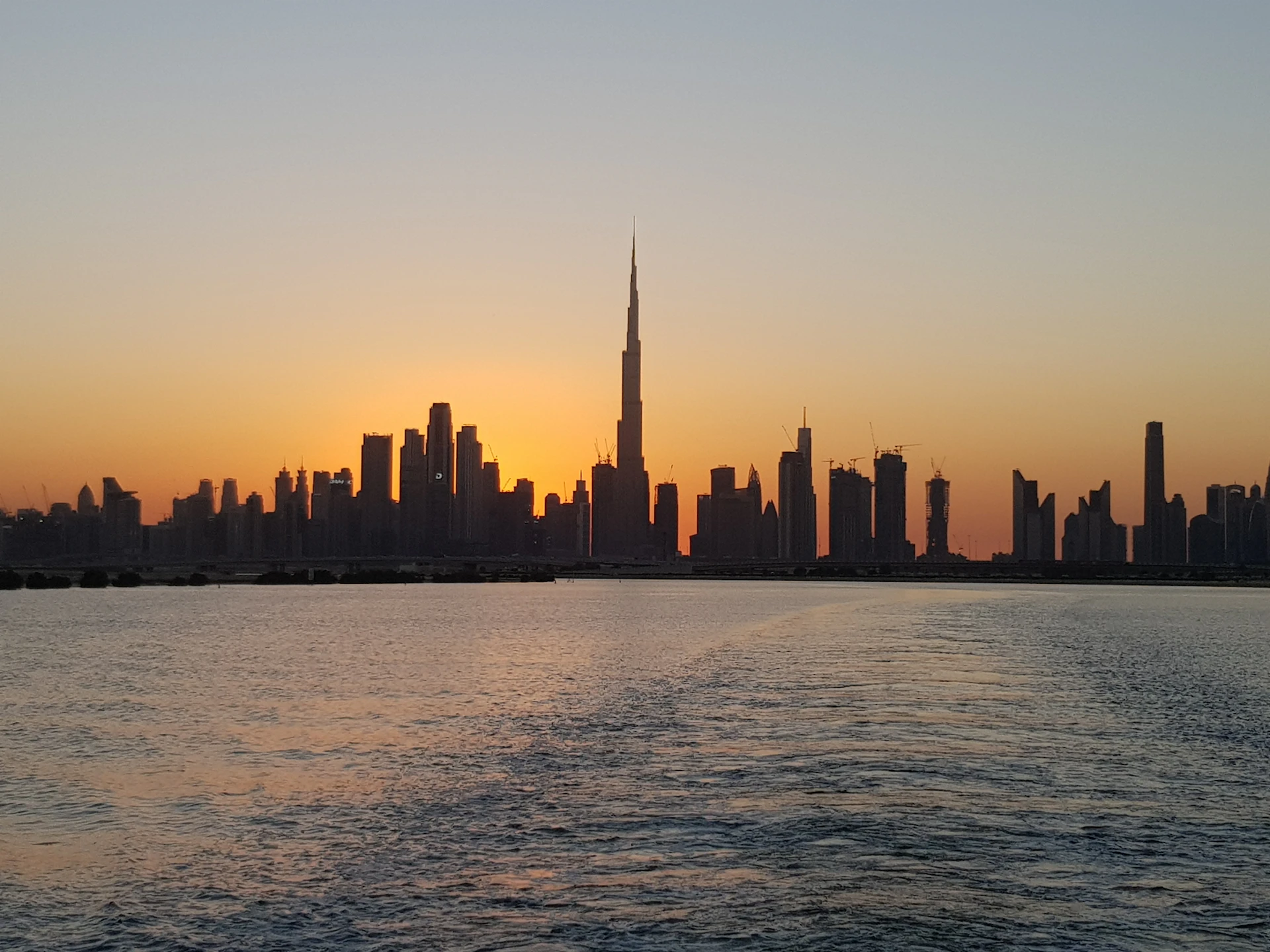 أفق دبي مع برج خليفة عند الغروب، كما يبدو من الماء