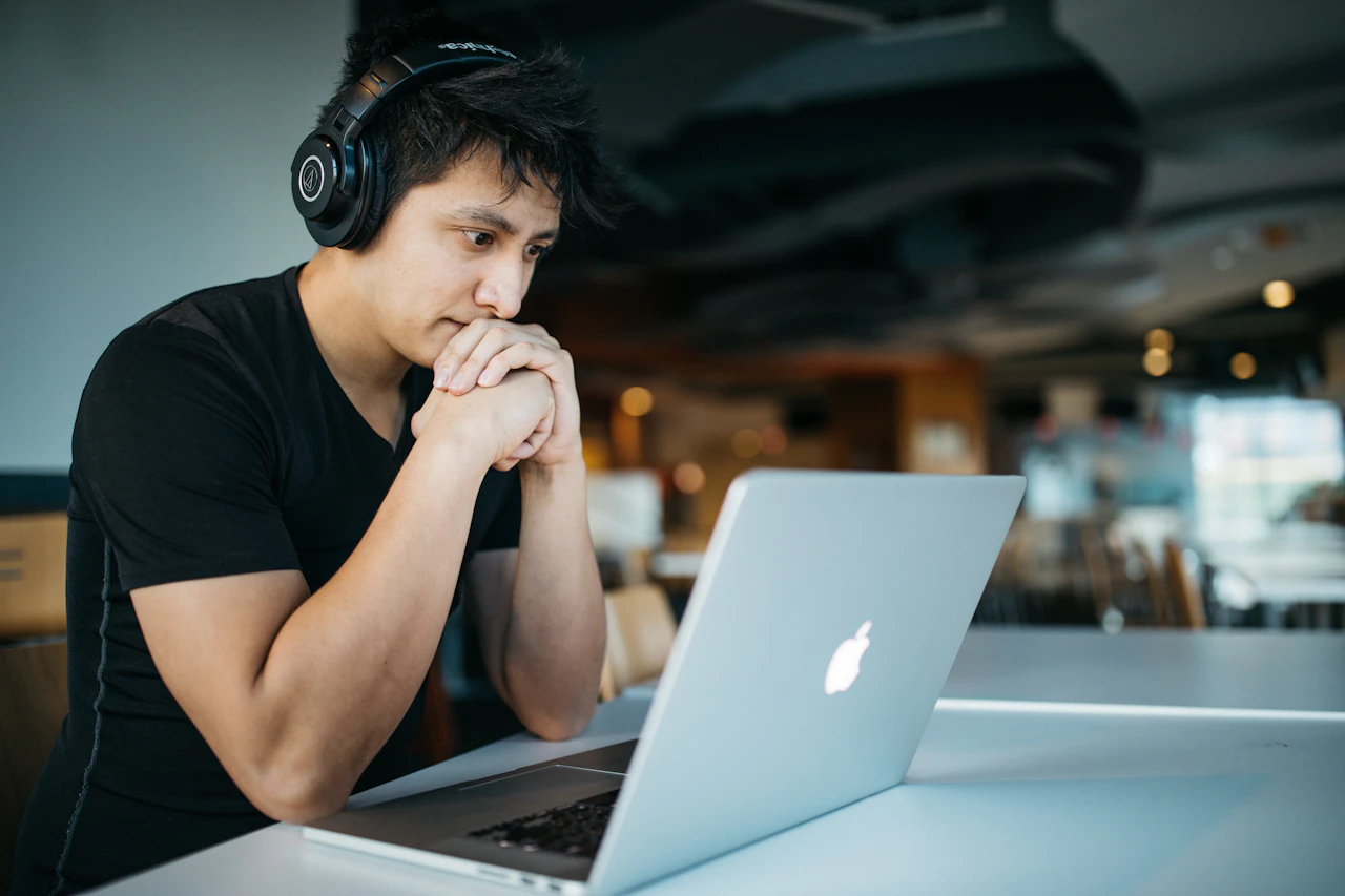 A student wearing headphones studying on a laptop