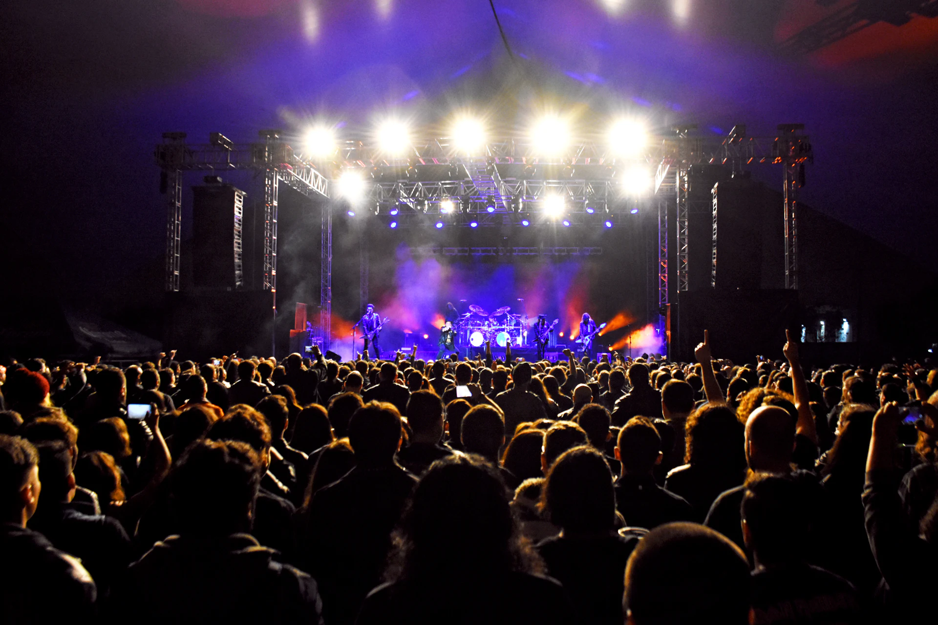 A crowd watching a concert under purple stage lights