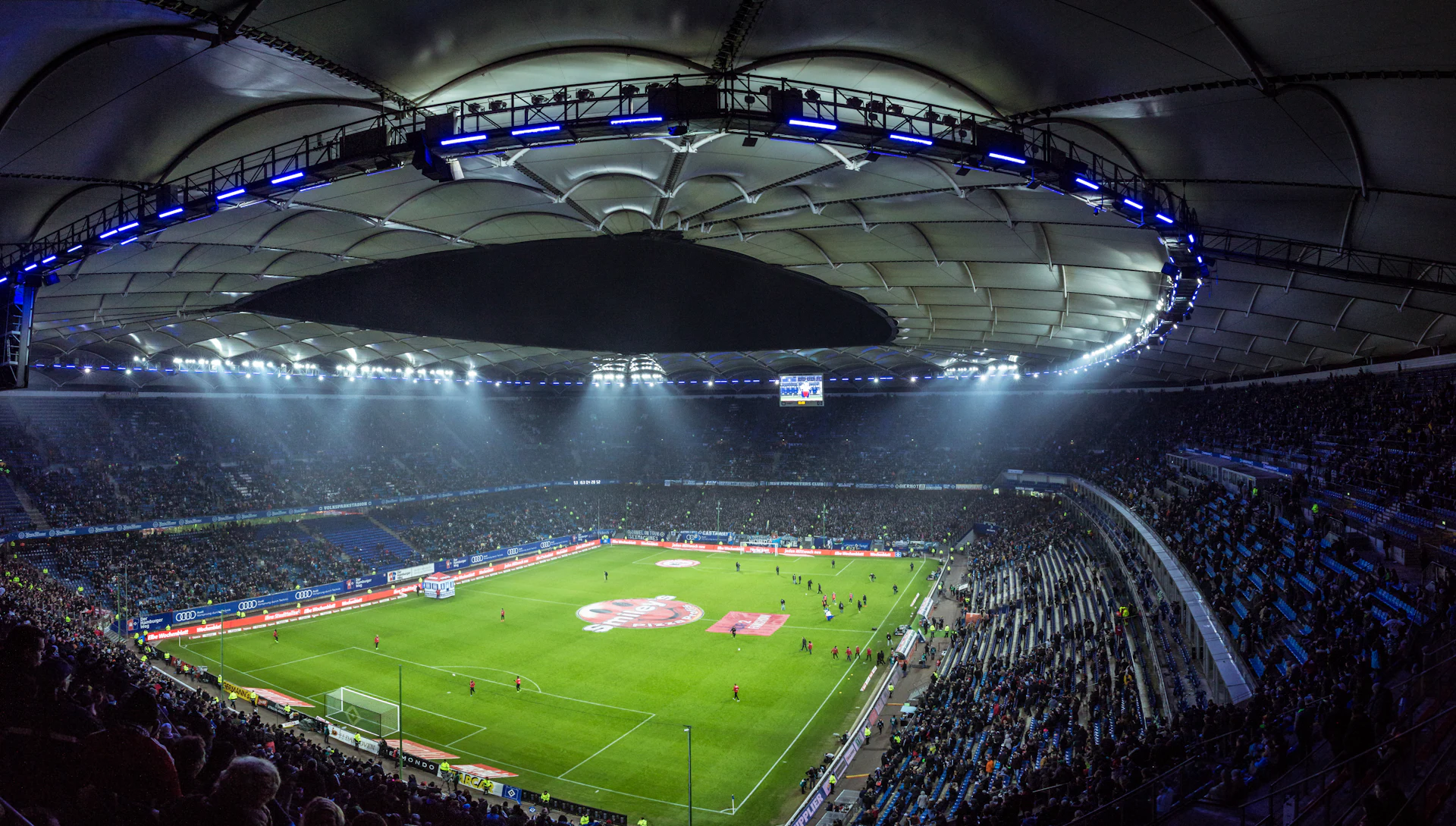 A floodlit football stadium seen from high in the stands
