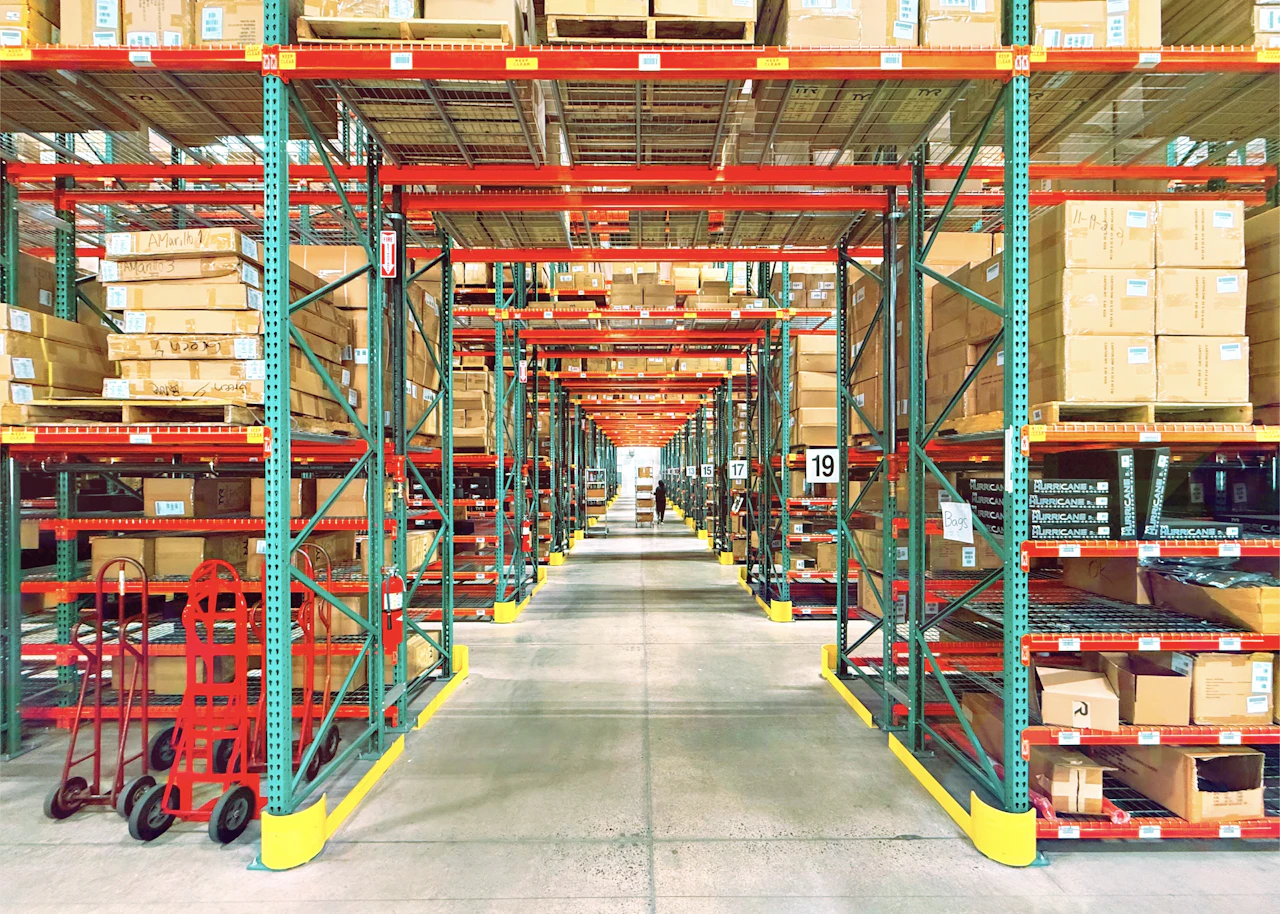 Tall rows of shelving stacked with goods in a large warehouse