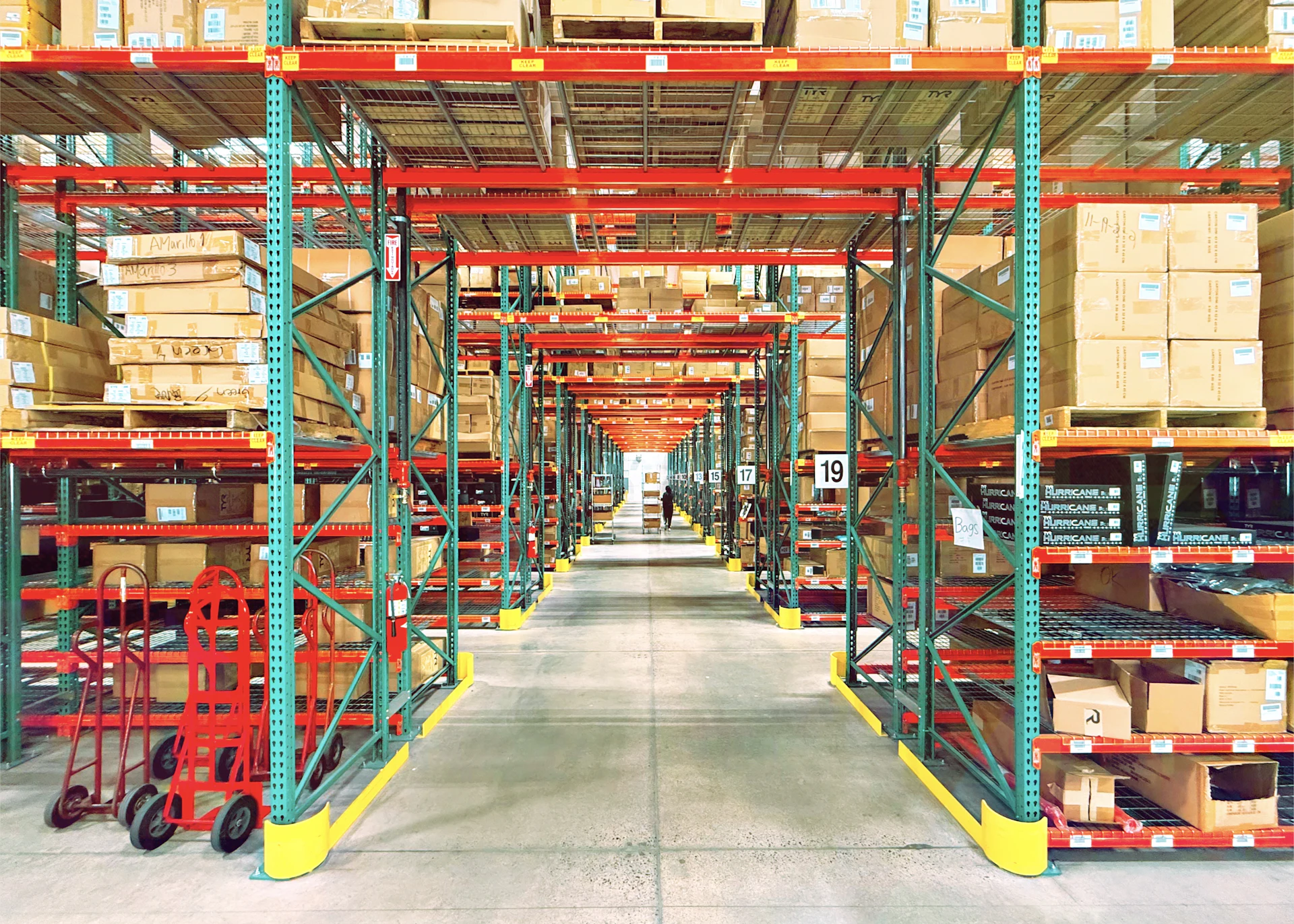 Tall rows of shelving stacked with goods in a large warehouse