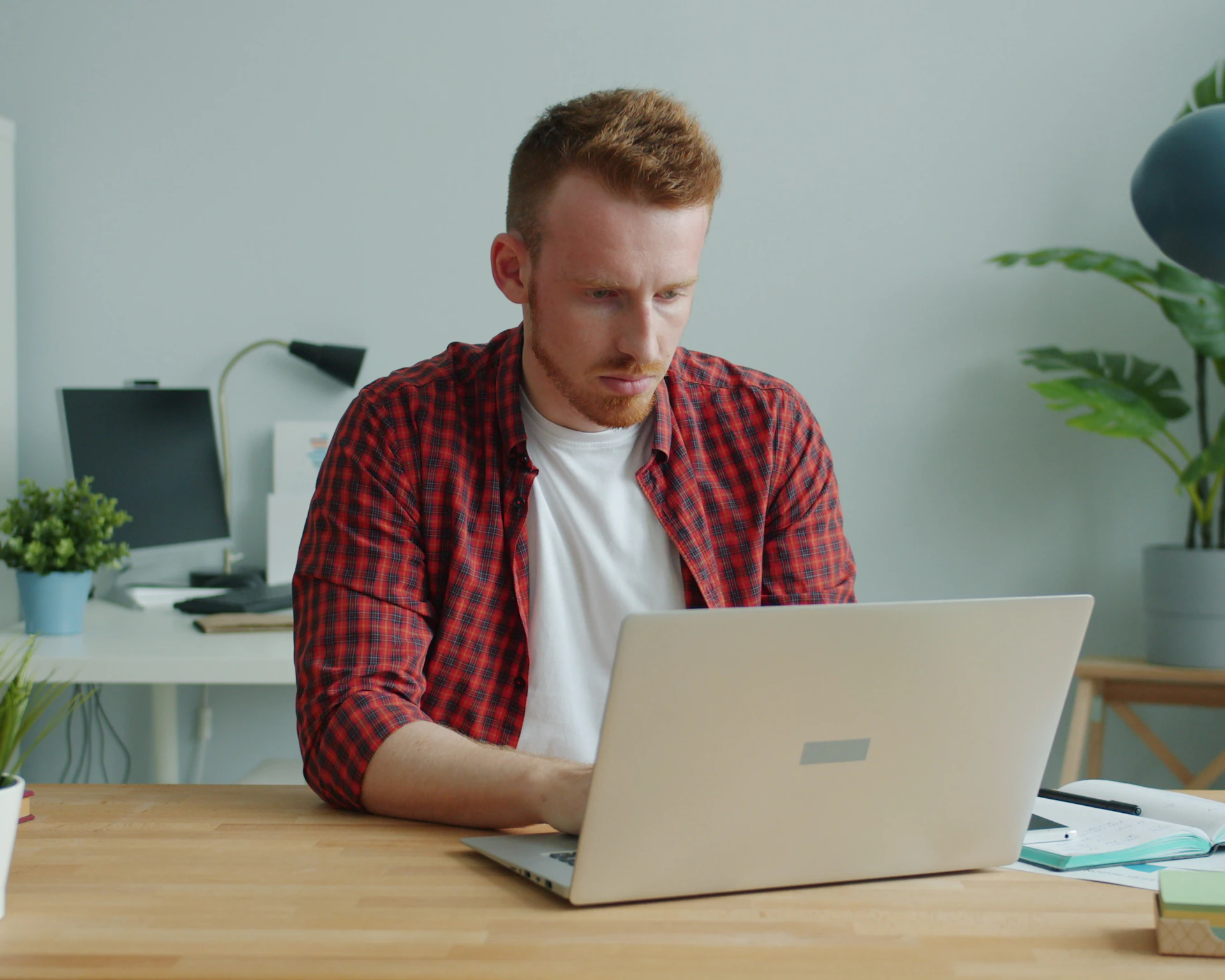 A man working on a laptop at a bright desk